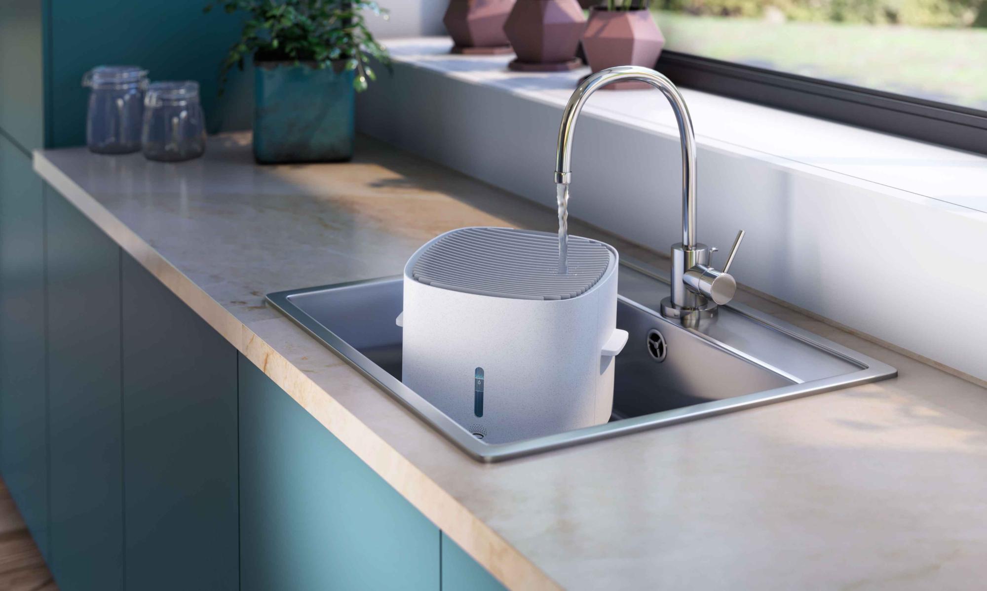 Attēlā redzama Philips 2in1 Climate Care ierīces uzpildīšana virtuves izlietnē, izceļot tās kompakto dizainu un uzpildes procesu ar skaidru ūdens līmeņa redzamību.