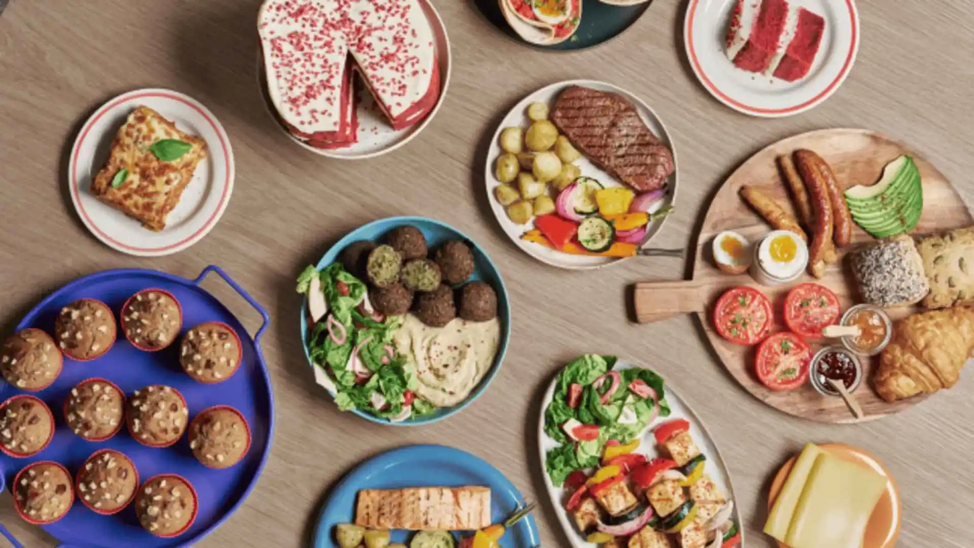 Fotoattēls no augšas, kurā redzamas Philips Airfryer kulinārijas iespējas virtuvē. Izceļ kraukšķīgos, veselīgos rezultātus dažādiem ēdieniem: kūkām, salātiem, grilētai gaļai un citiem, demonstrējot Philips Airfryer izcilību.