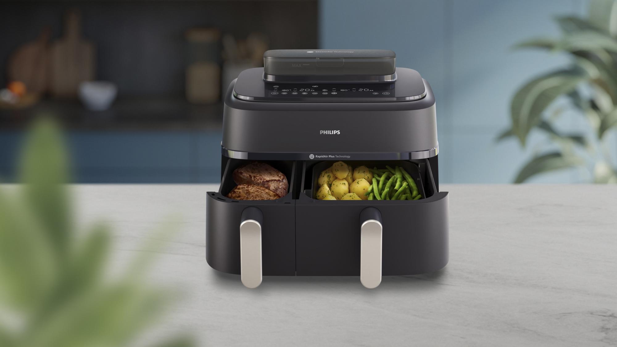 Philips divu grozu gaisa fritieri ar atvērtām atvilktnēm, kurās ir steiks, kartupeļi un zaļās pupiņas