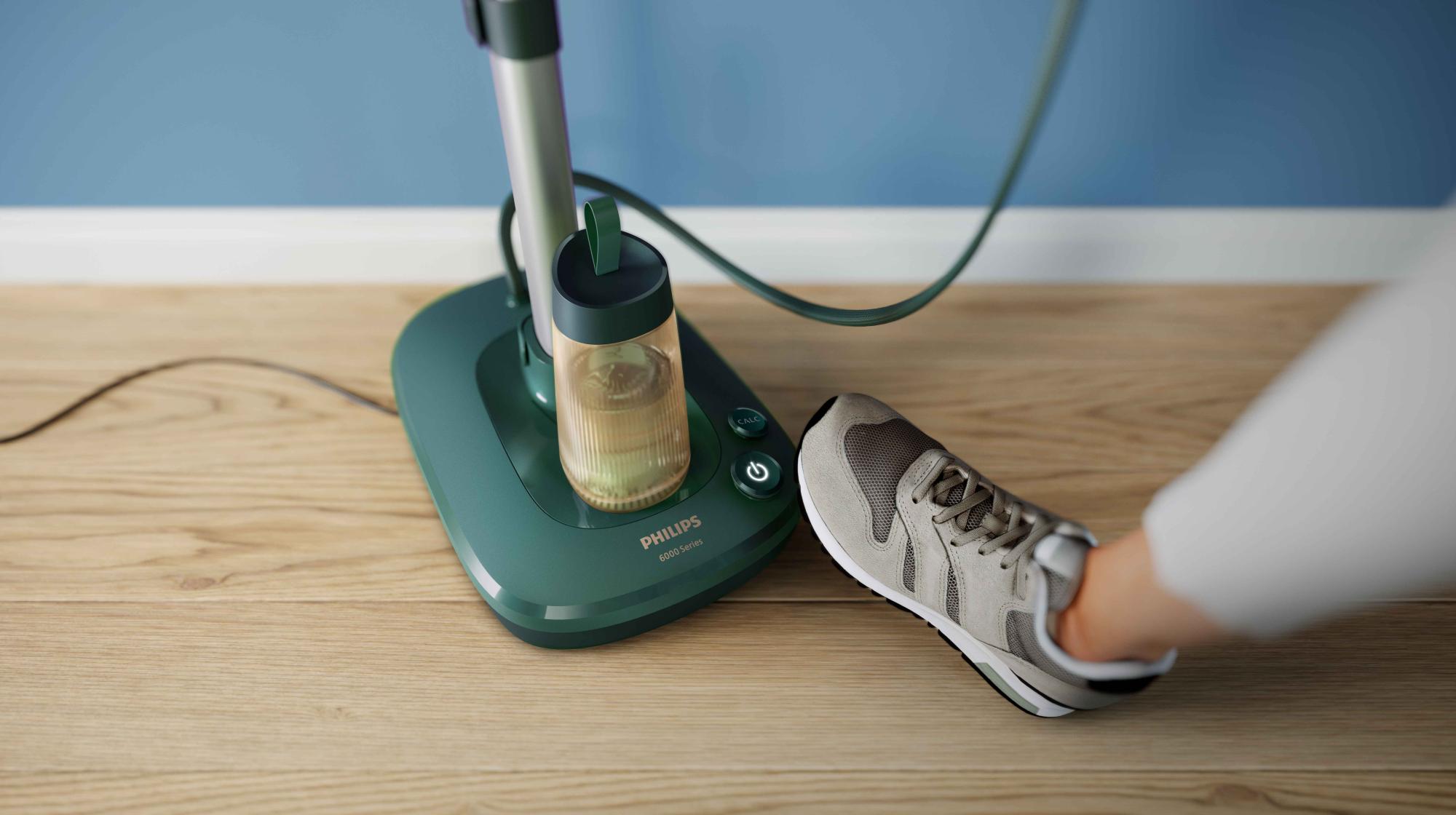 Philips universālais All-in-One apģērba tvaicētājs ar stavīnu uz koka grīdas blakus apaviem, demonstrējot pilnīgu mājas tekstilizstrādājumu kopšanas risinājumu.
