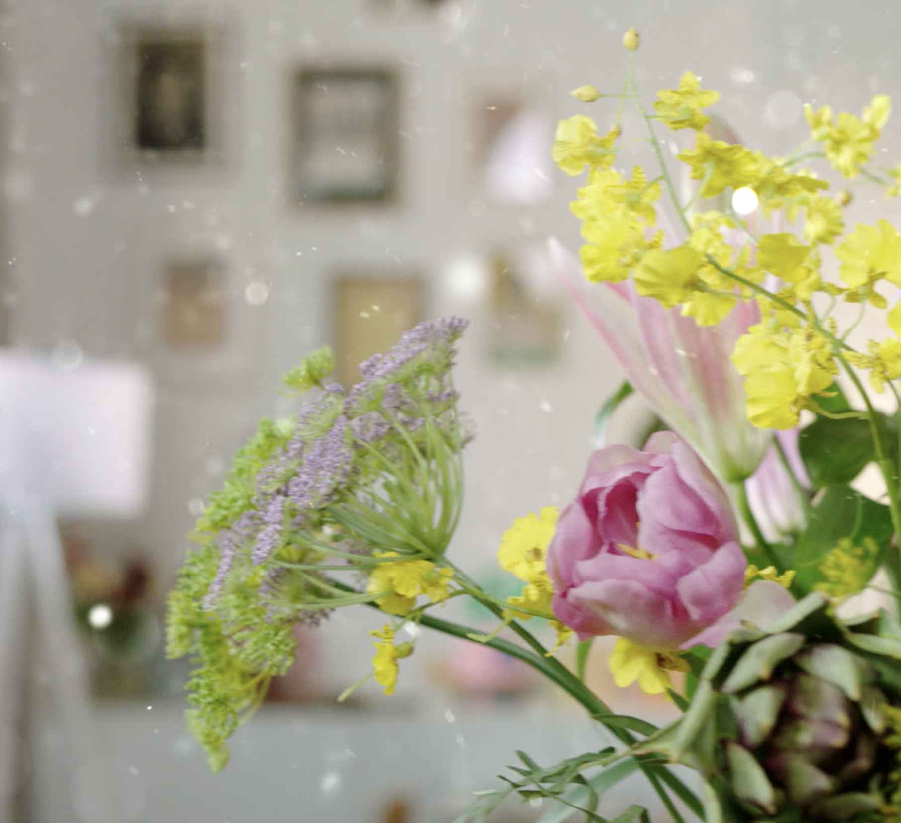 Pasteļtoņu ziedu kompozīcijas, rozā tulpes, dzeltenu orhideju un zaļu lapotnes tuvplāns. Philips Climate Care: dabiski attīriet gaisu ar istabas augiem; ilgtspējīga, svaiga estētika.