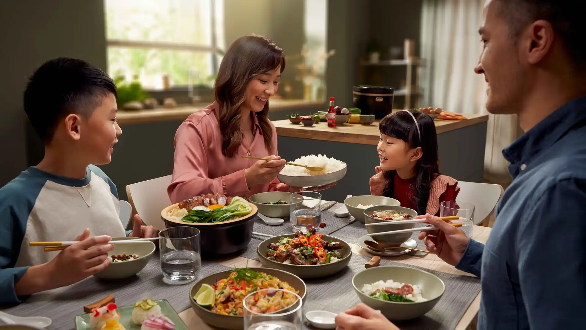 Ģimene bauda dažādus Āzijas ēdienus, kas pagatavoti, izmantojot Philips plītis. Rīsu vārītājs novietots uz galda, kas klāts ģimenes vakariņām.