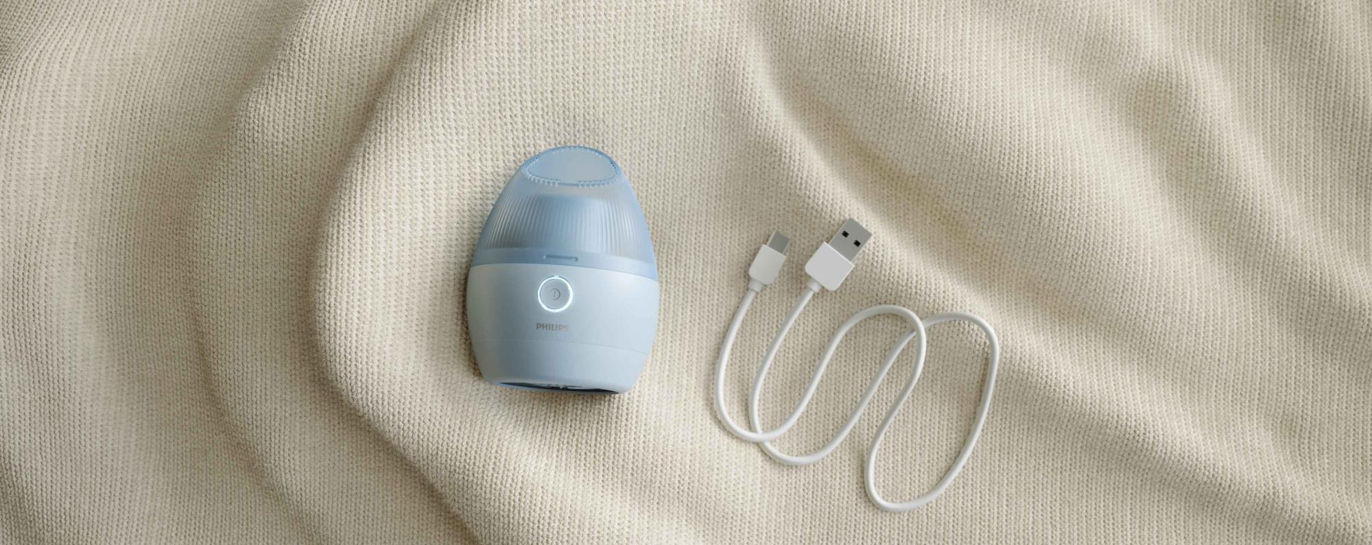 Philips Essentials Garment Care auduma skuveklis gaiši zilā krāsā ar uzlādes vadu. Izbaudiet izcilu auduma atjaunošanu: kompakts, efektīvs un viegli lietojams jebkuram audumam.