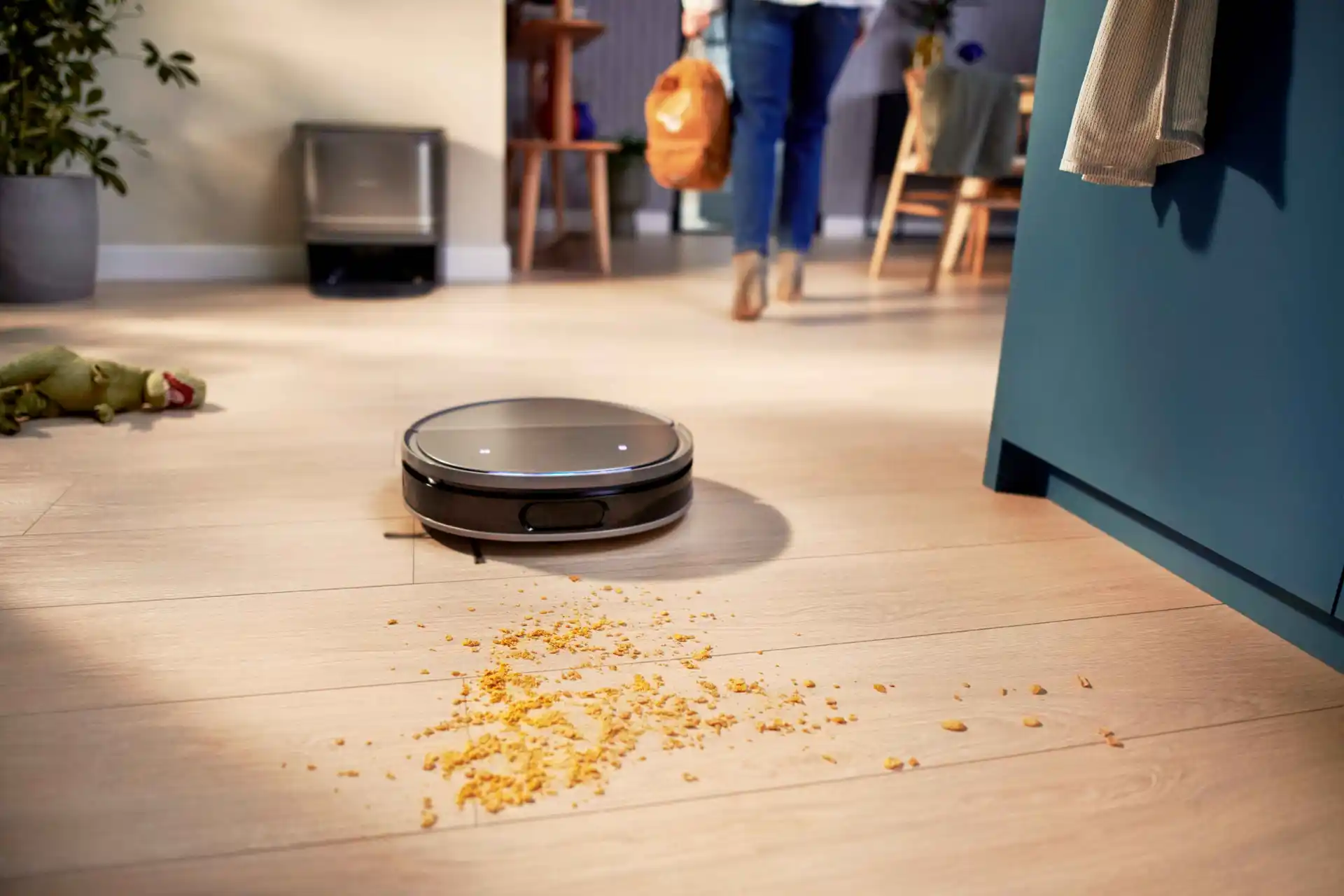 Philips Floor Care robotizētais putekļsūcējs ar automātisku netīrumu savākšanu pārvietojas pa vieglu koka grīdu, noņemot drupačas, ideāli piemērots tīrīšanai bez piepūles.