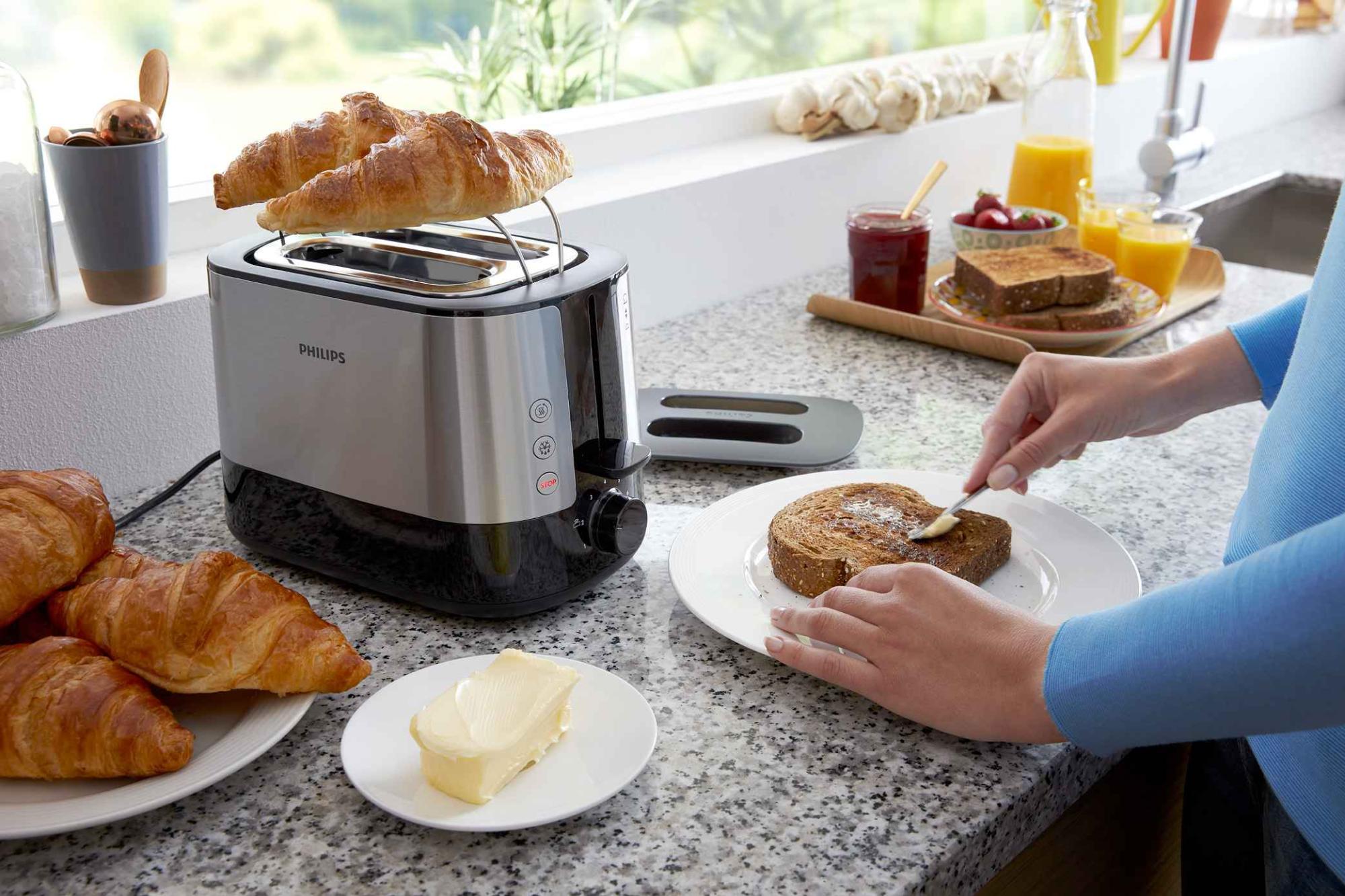 Philips grili un tosteri: augstākās kvalitātes melns tosteris ar nerūsējošā tērauda akcentiem, kas grauzdē kruasānu kā daļu no gardēžu virtuves brokastu klājuma.