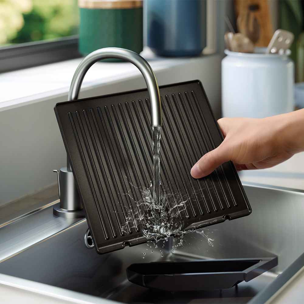 Philips grilu un tosteru grila plātnes mazgāšana modernā virtuves izlietnē. Attēlā redzama vienkārša tīrīšana, noņemama pilienu paplāte un augstas kvalitātes dizains.