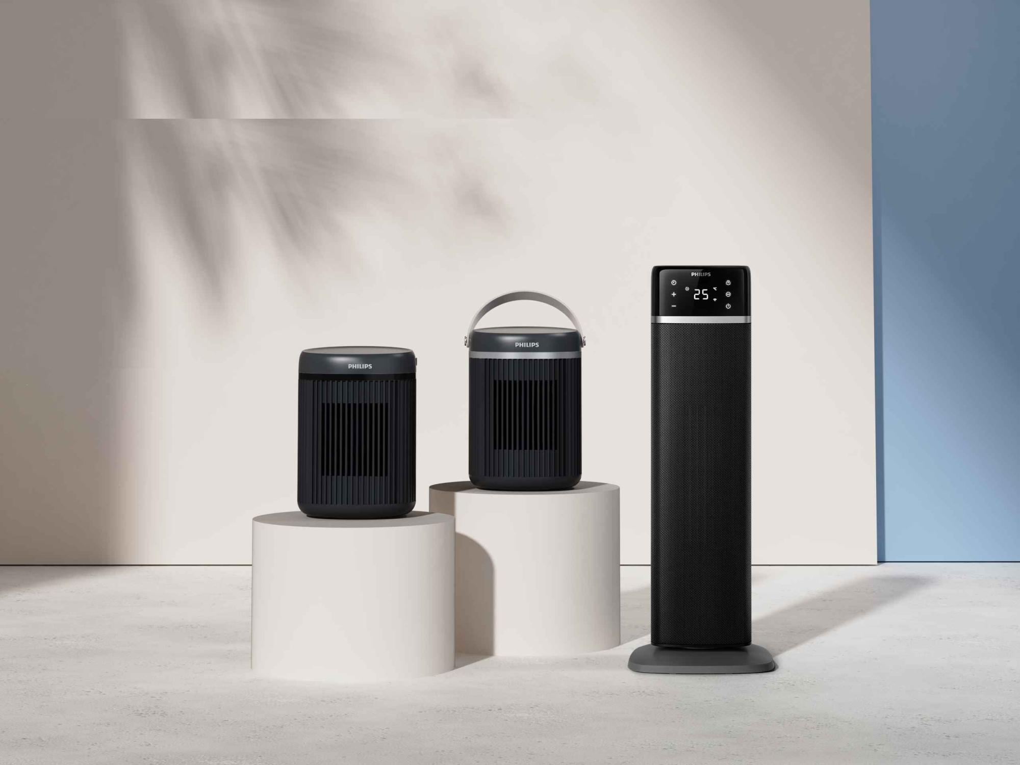 Studijas fotoattēls ar trim Philips sildītāju modeļiem no Climate Care līnijas. Iekļauts torņa sildītājs ar redzamu 25 grādu displeju un divi pārnēsājami, dizainam pielāgoti sildītāji ar rokturiem.