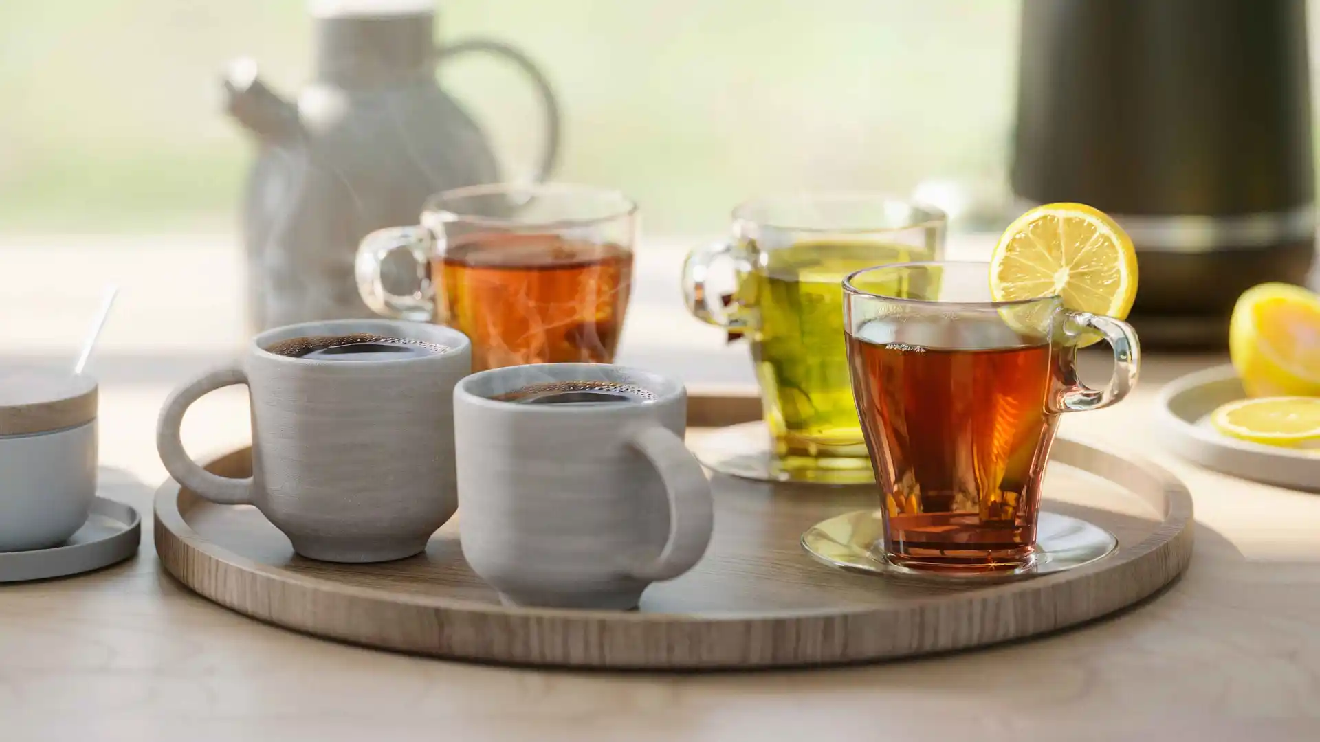 Karsto dzērienu izlase, tostarp kafija un tēja, pasniegta keramikas krūzēs un caurspīdīgās stikla tasītēs uz apaļas koka paplātes, fonā – moderna Philips tējkanna. Philips tējkannas piedāvā modernu dizainu.