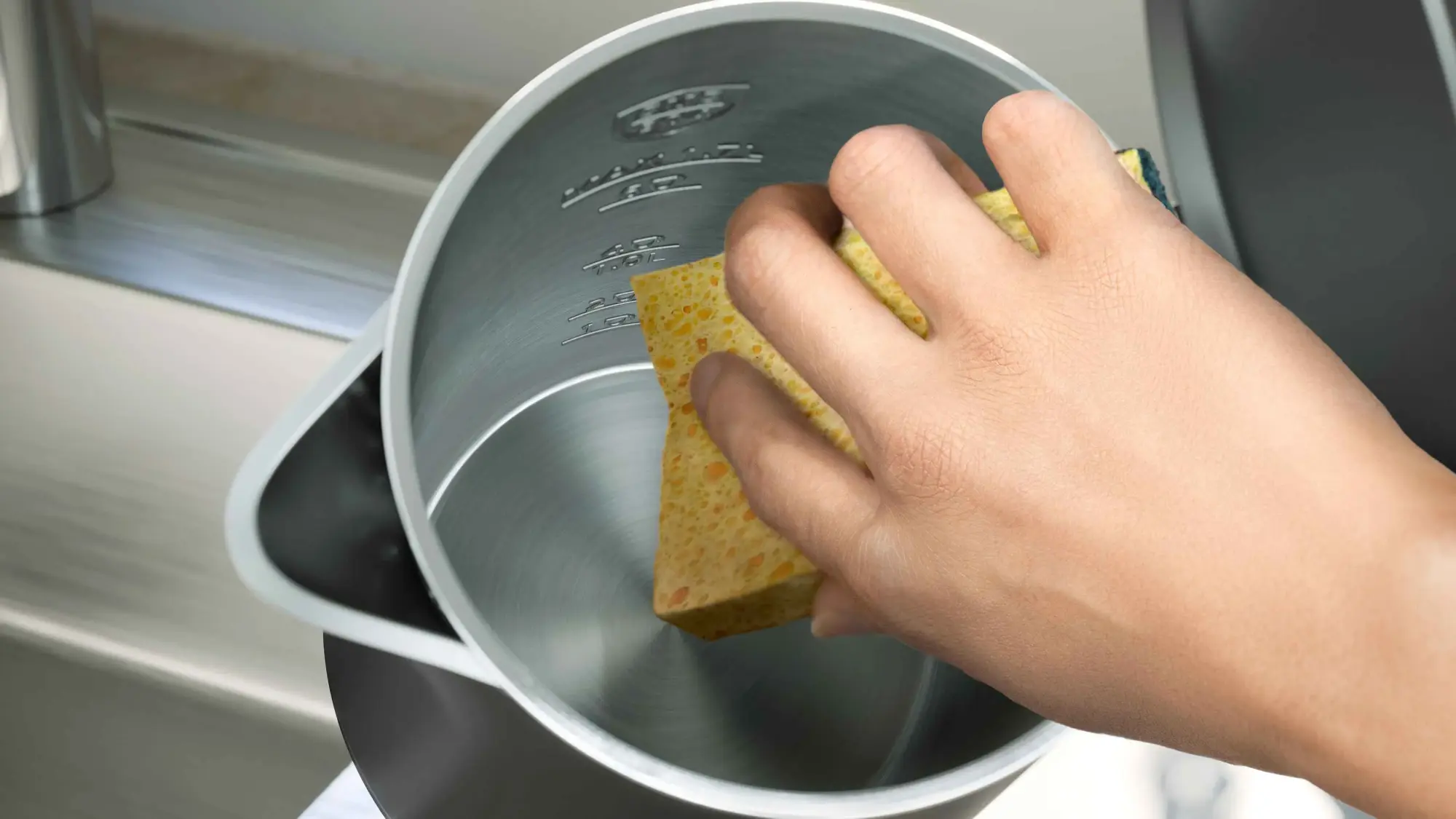 Philips tējkannas attēls: ar roku tiek notīrīts nerūsējošā tērauda iekšpuse, uzsverot vieglu tīrīšanu un izcilu dizainu. Matētā metāla iekšpusei ir skaidras ūdens līmeņa atzīmes papildu ērtībai.