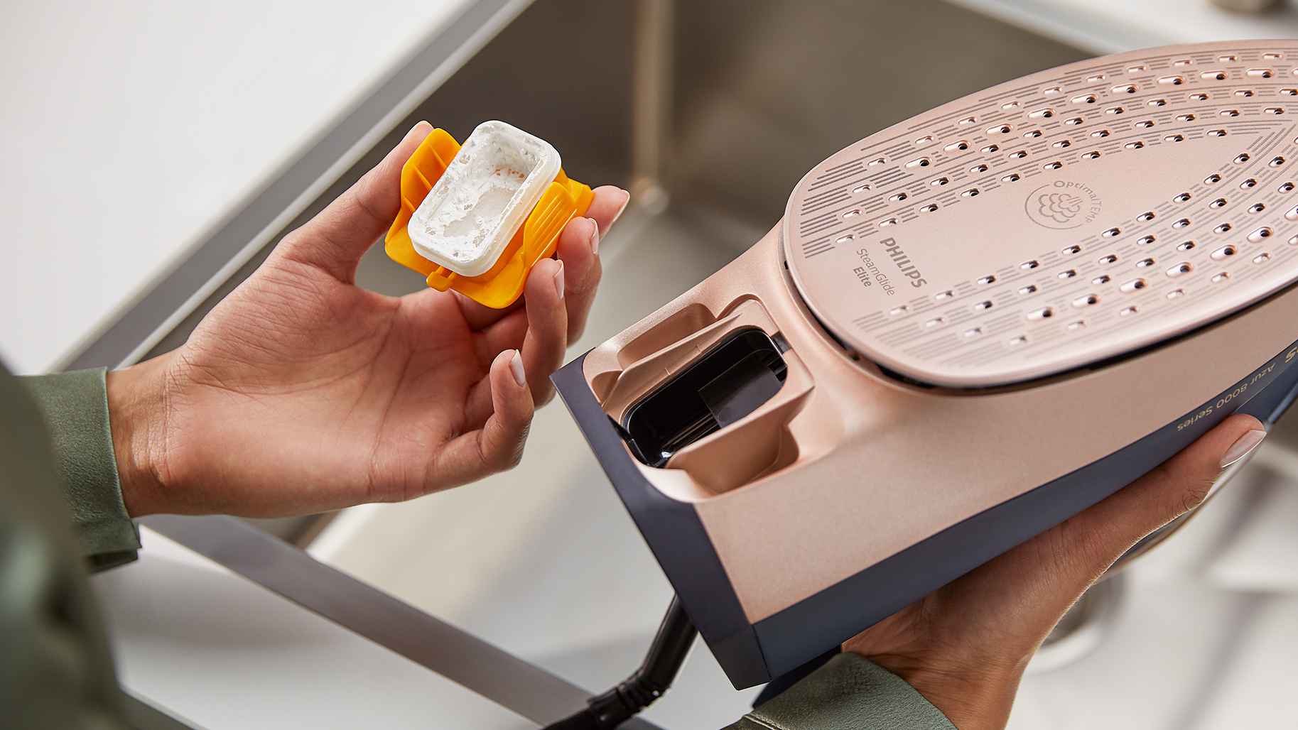 Philips tvaika gludekļi: SteamGlide Elite modelis. Tuvplānā redzama viegli noņemama kaļķakmens tvertne, kas nodrošina izcilu veiktspēju un apkopi.