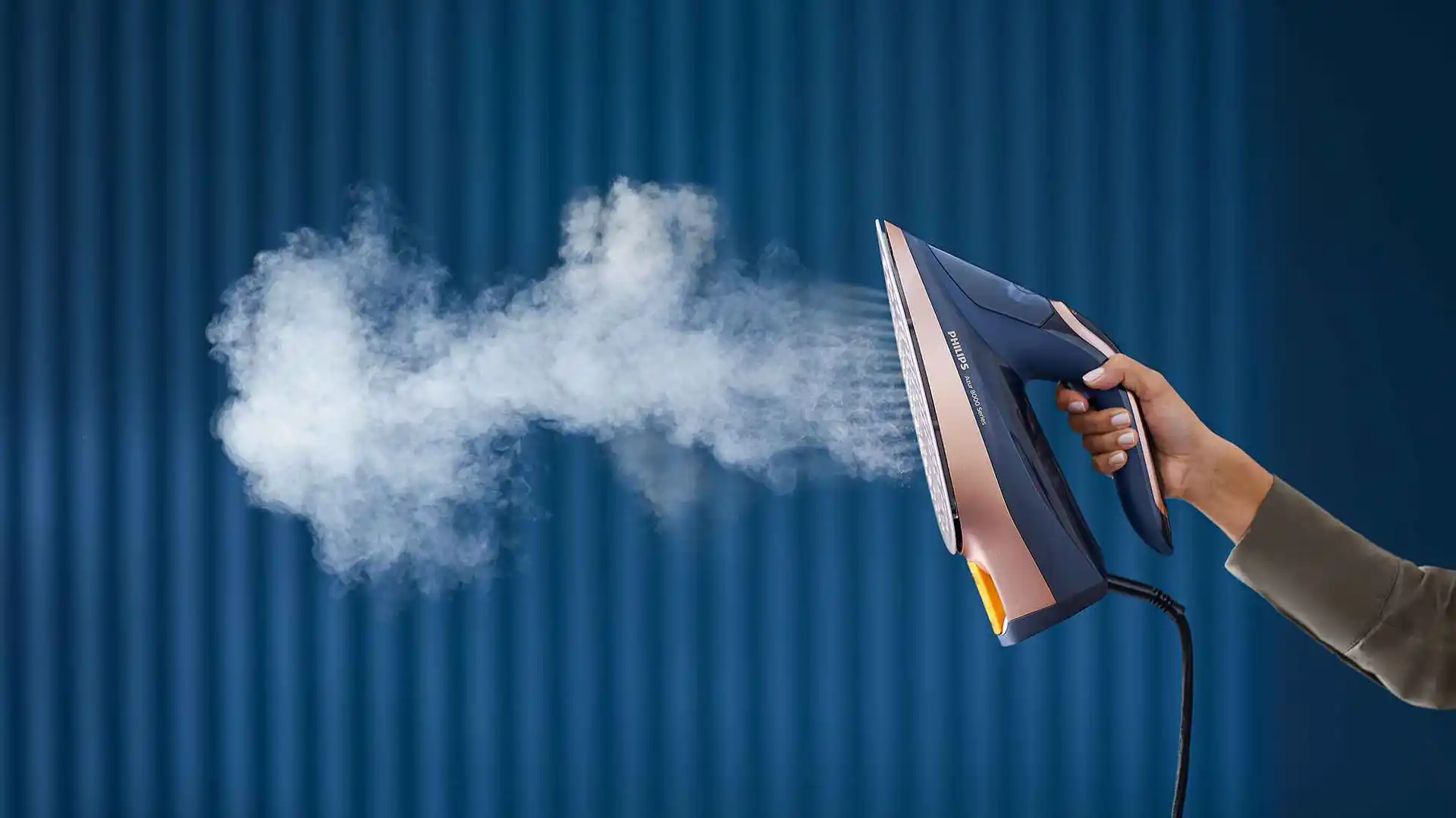 Philips tvaika gludekļi: rokā turot Philips apģērbu kopšanas gludekli, izdalās tvaiks, kas demonstrē spēcīgu grumbu likvidēšanu. Izcils dizains nodrošina profesionālu gludināšanas pieredzi.