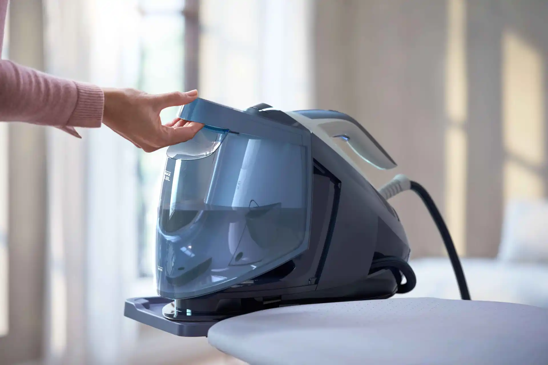 Philips tvaika ģeneratori nodrošina vislabāko apģērbu kopšanu. Fotoattēlā redzams lietotājs, kurš uzpilda Philips gludināšanas sistēmas noņemamo ūdens tvertni, demonstrējot tā lietošanas ērtumu un jaudīgo tvaika padevi.