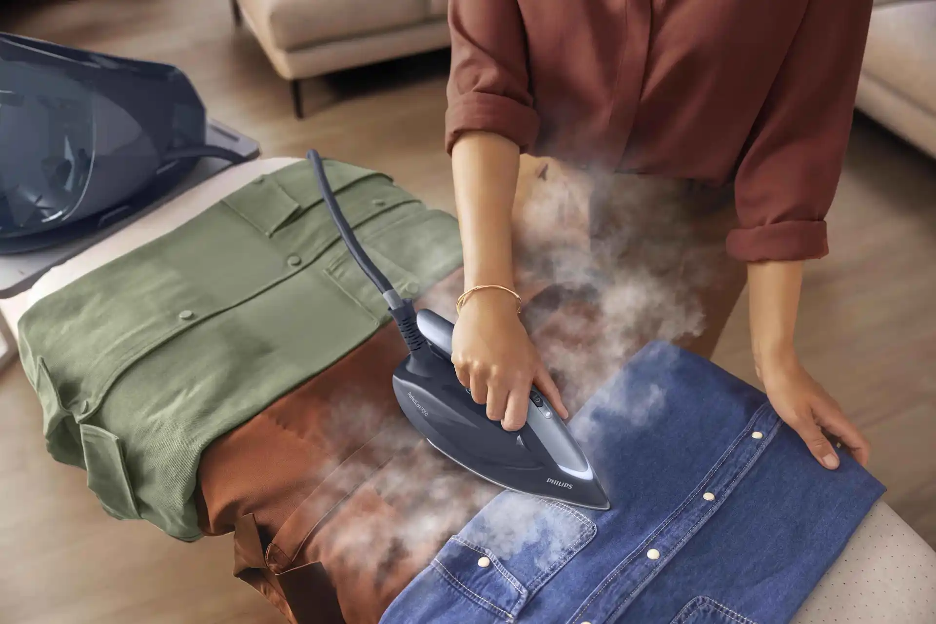 Philips gludināšanas sistēmas: Džinsa krekla tvaicēšana ar Philips PerfectCare 7000 tvaika ģeneratoru. Parāda spēcīgu grumbu likvidēšanu.
