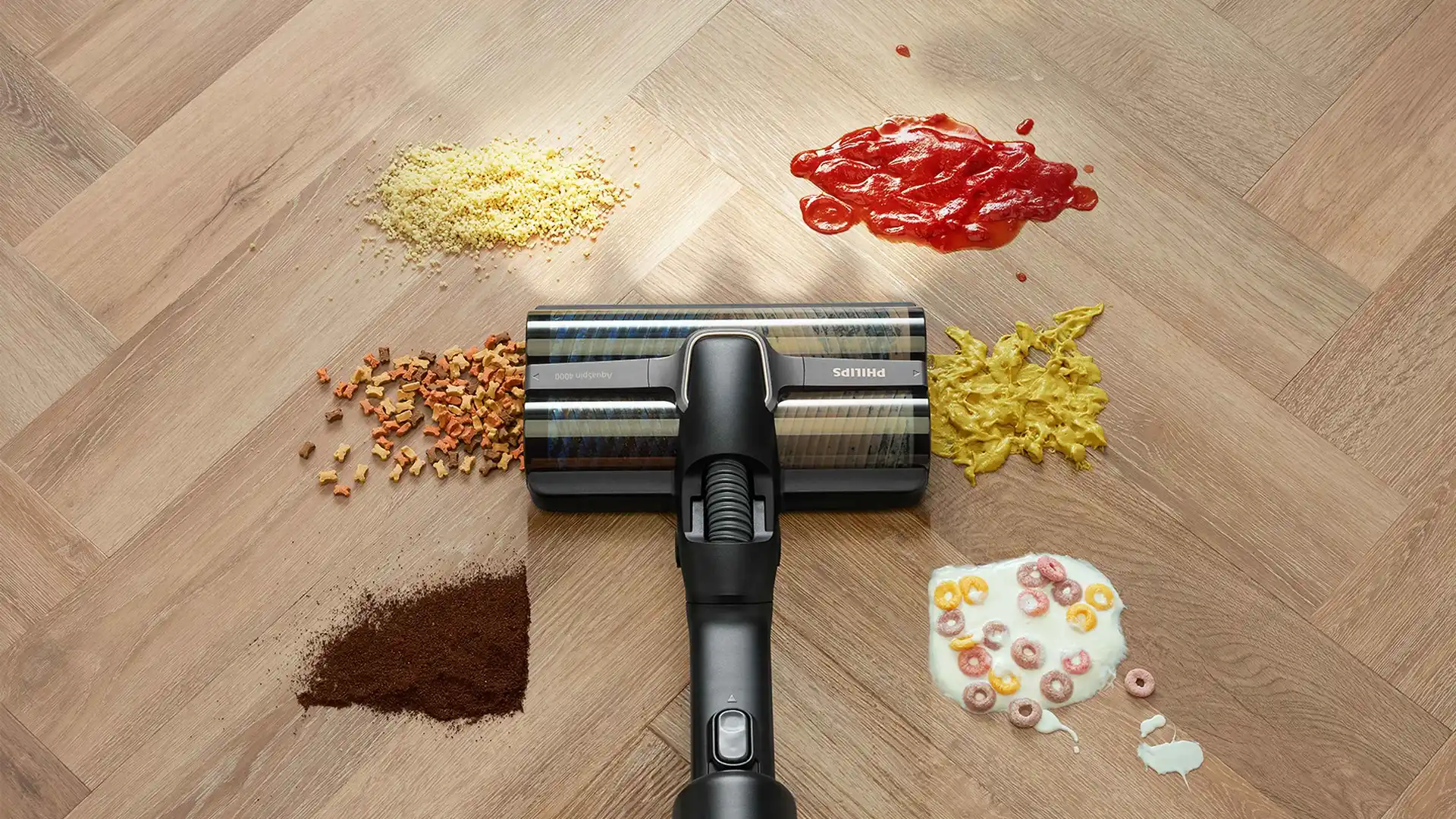 Philips Vac & Wash tīra dažādus netīrumus (kečupu, pārslas, kafiju u. c.) uz gaišas koka grīdas, demonstrējot savu izcilo universālo tīrīšanas jaudu.