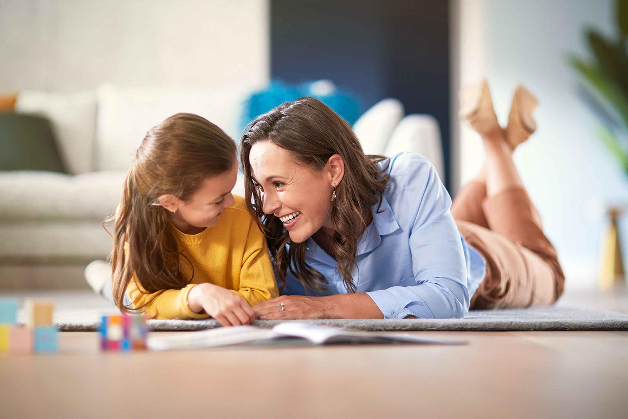 Philips putekļu sūcēji nodrošina izcilu tīrīšanas veiktspēju. Māte un meita guļ uz paklāja un skatās viena uz otru bez putekļiem esošā vidē, radot mājīgu un veselīgu atmosfēru.