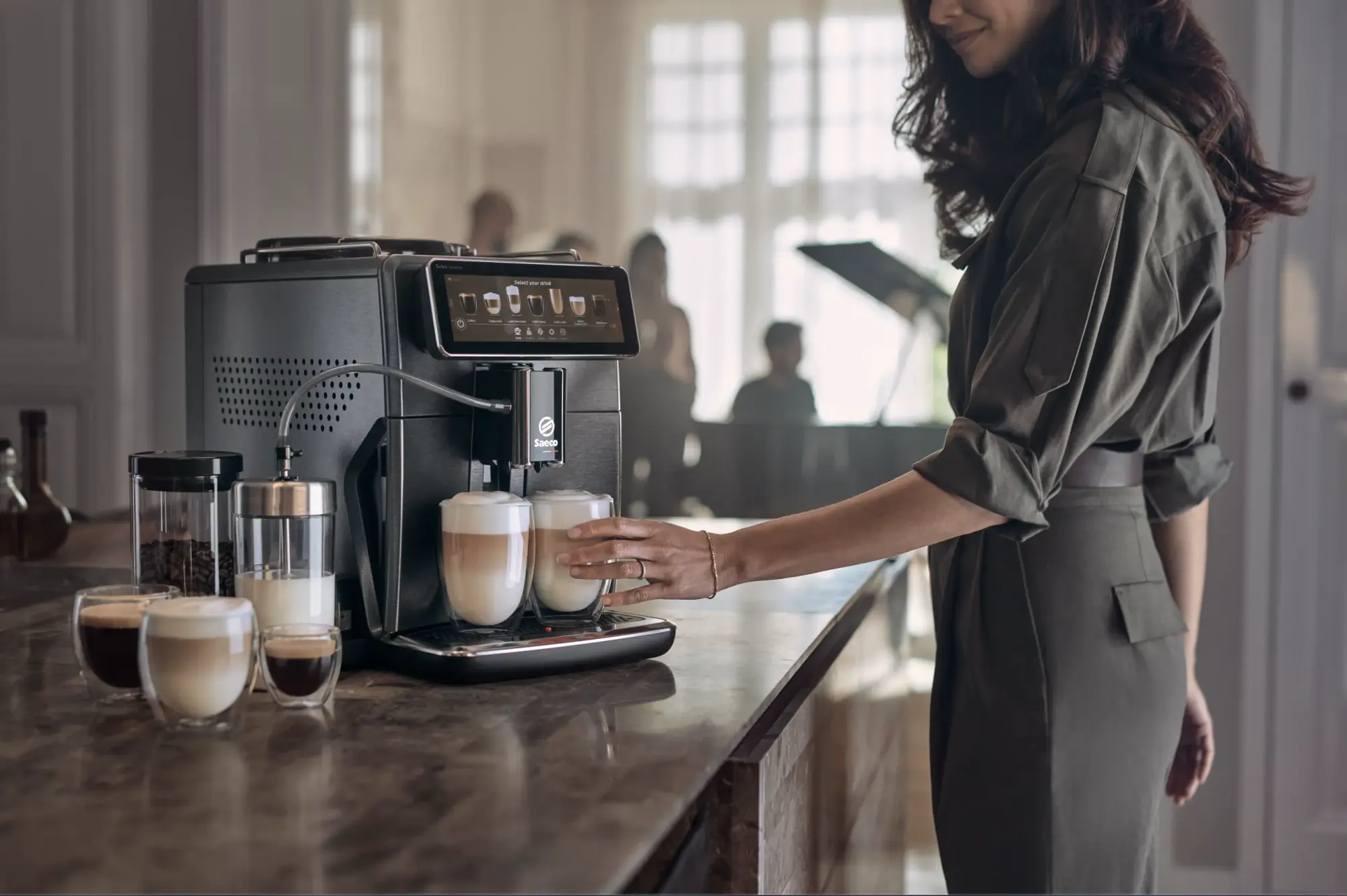 10 copy Sieviete paņem latte no Philips Saeco espresso automāta, izceļot tā skārienekrānu, augstākās kvalitātes dizainu un lietošanas ērtumu, lai pagatavotu izcilu kafiju. Redzamas svaigas pupiņas un piens.